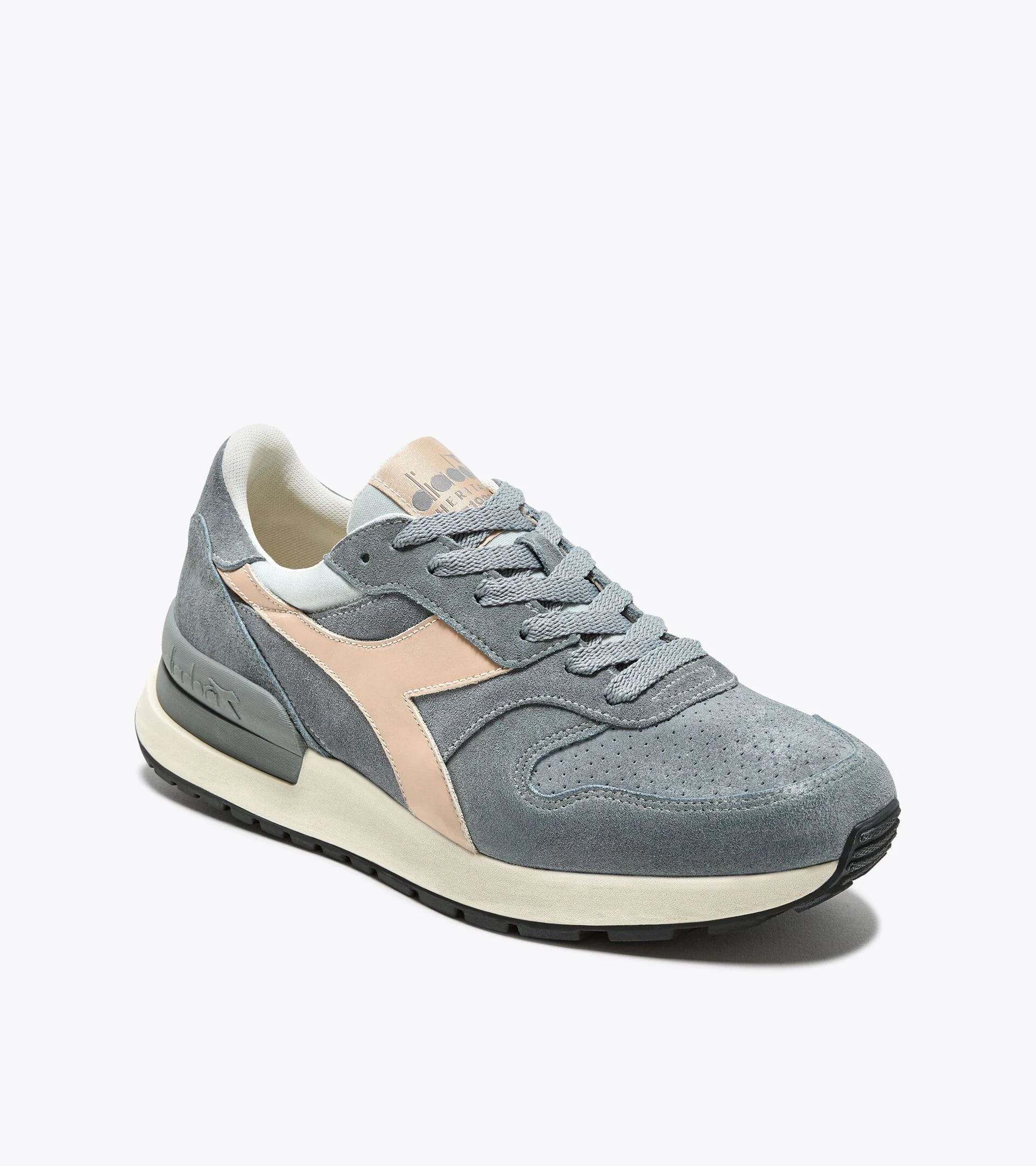 A single Ace Rivington Diadora Conquest Suede SW - high-rise color shoe features a grey suede upper with a beige Diadora logo on the side, grey laces, and a beige midsole with a black outsole. The sneaker has a retro design with a comfortable and stylish appearance.