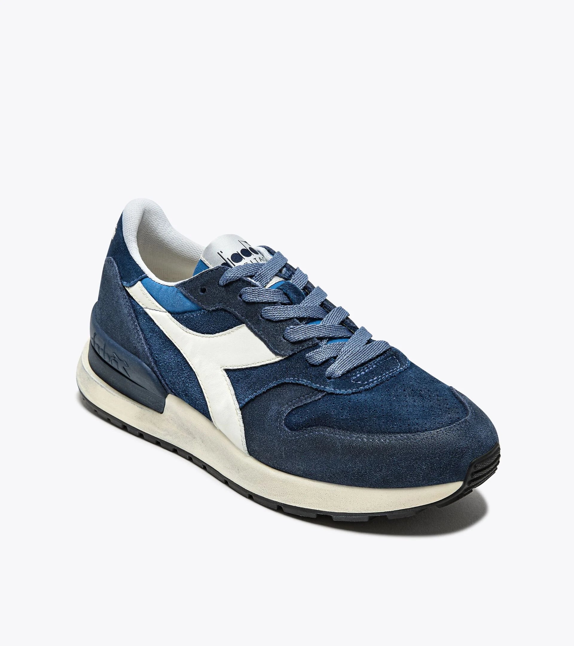 A right-pair side view of an Ace Rivington Diadora Conquest Suede SW sneaker in Colonel Blue features a dark blue suede upper with a white leather logo stripe on the side, a white midsole, and a black rubber outsole. The laces and tongue are also blue, and the heel has a textured design for added style.