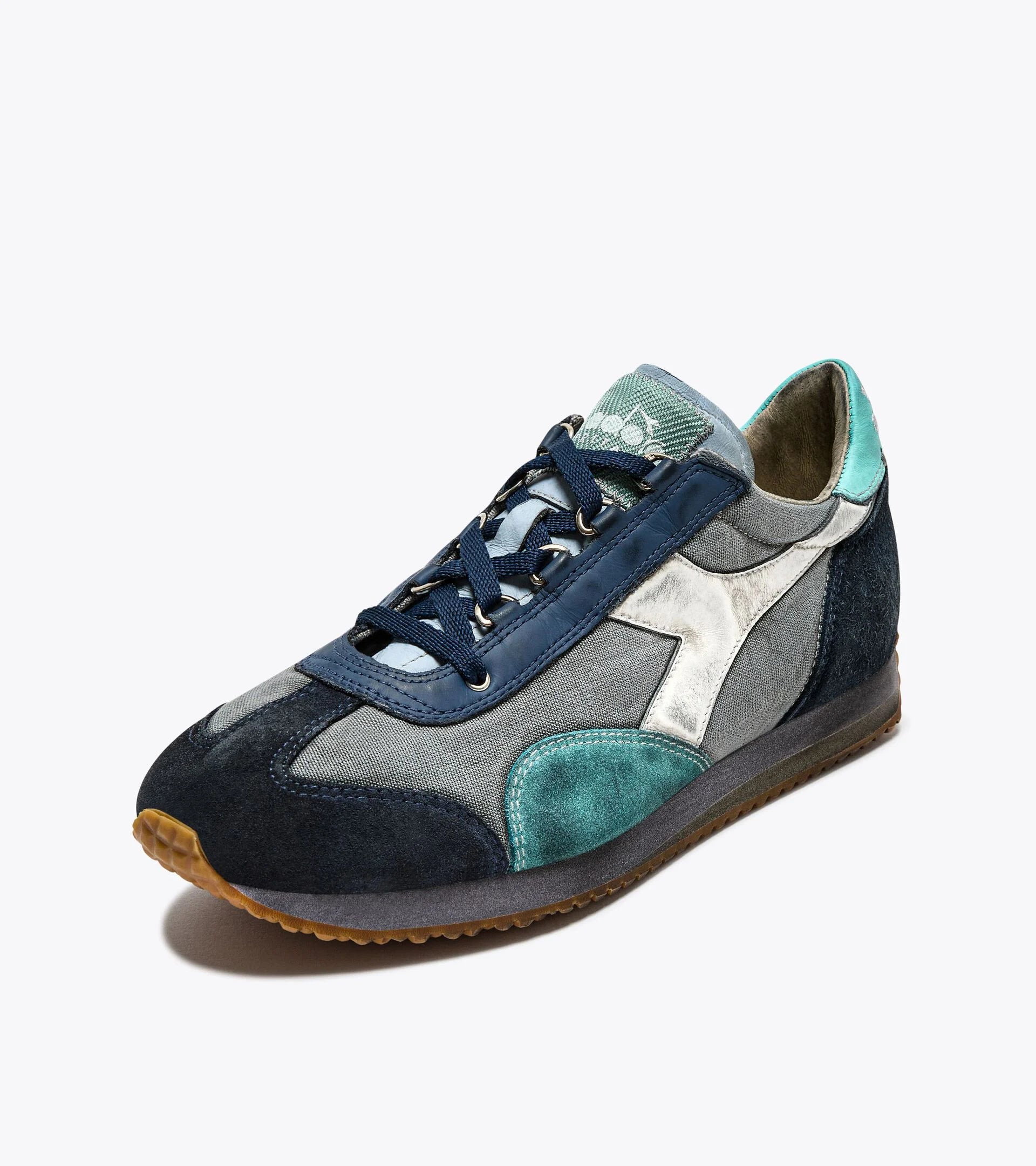 A left-pair upper side view of the Ace Rivington Diadora - Equipe Dirty SW EVO in Light Sky Blue features a combination of materials, including denim and suede, with a mix of blue, teal, and white colors. The design includes a white Diadora logo on the side, blue laces, and a gum rubber sole. The sneaker has a vintage, worn-in look with a modern twist, making it both fashionable and comfortable.