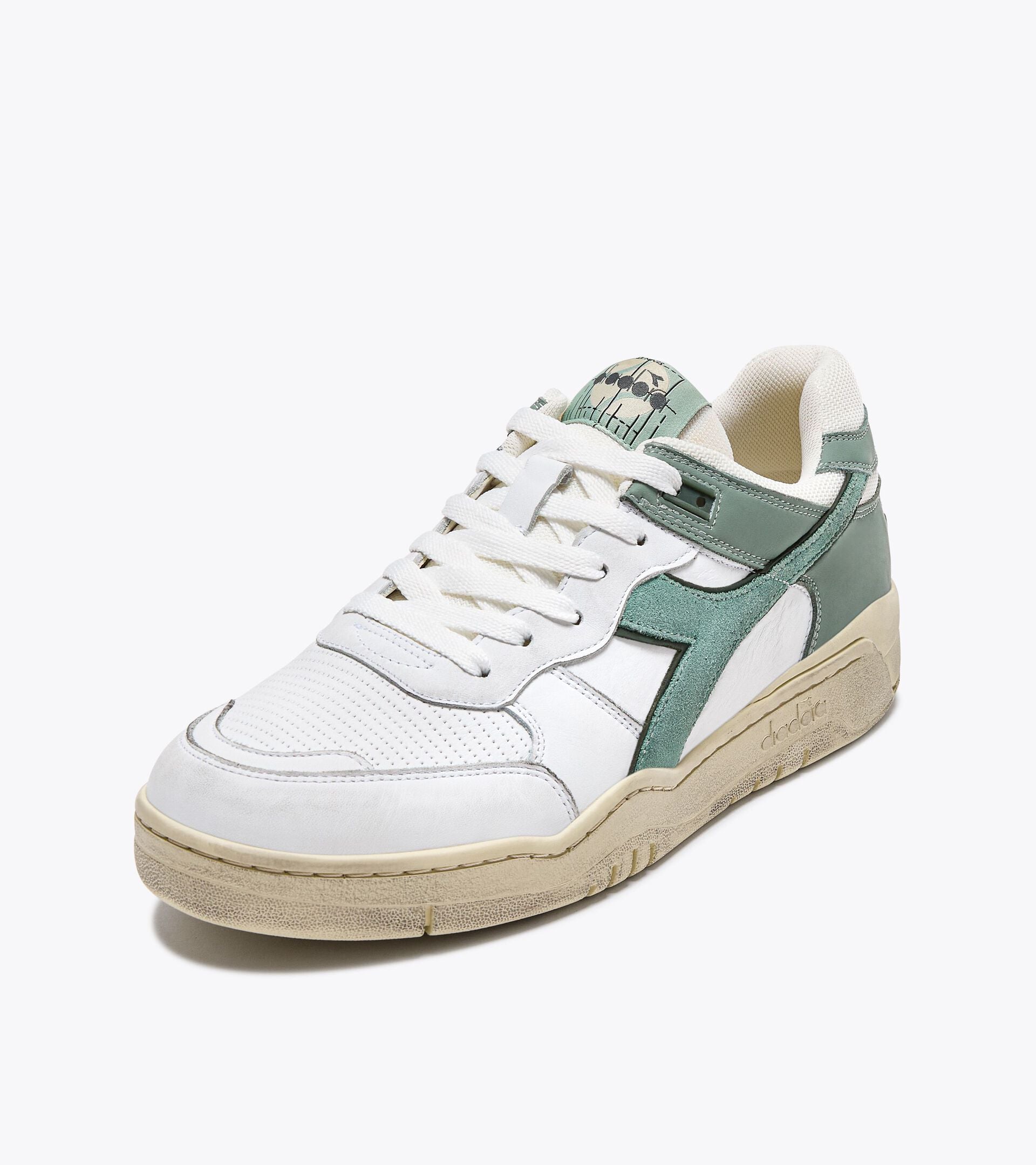 Ace Rivington Diadora B. 560 USED - Iceberg Green shoe features a white leather upper with green suede accents, a perforated toe box, and a beige rubber sole. The tongue has a green label with a graphic design, and the shoe has white laces.