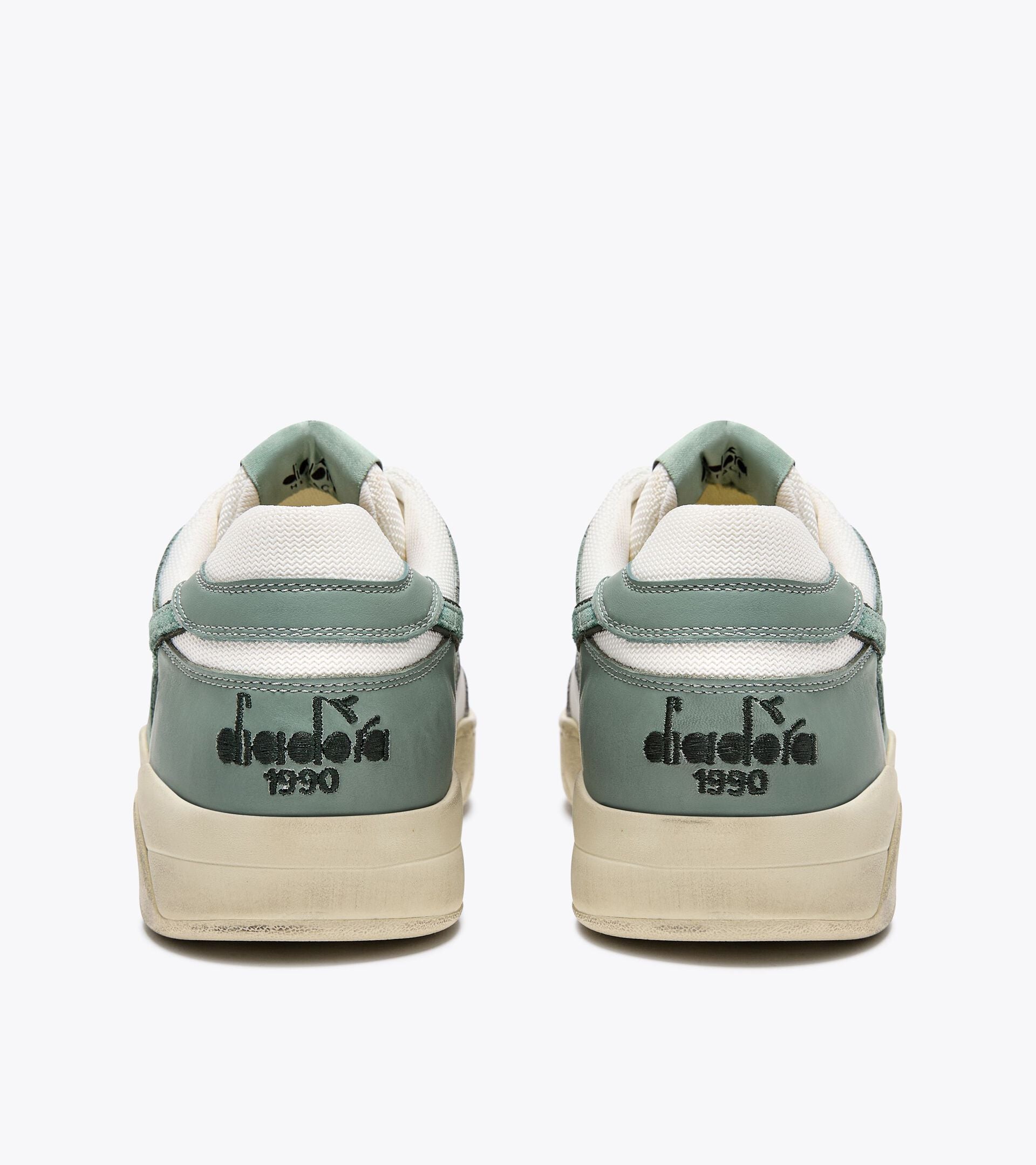 Rear view of a pair of Ace Rivington Diadora B. 560 USED - Iceberg Green shoes features a combination of green and white materials with the Diadora logo and '1990' printed in black on the heel.