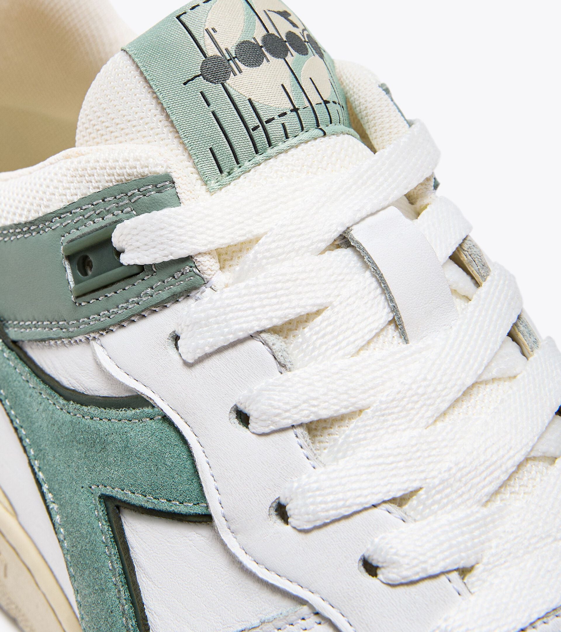 Close-up of the Ace Rivington Diadora B. 560 USED - Iceberg Green showcasing the white laces, green and white leather upper, and the unique design on the tongue with black dots and lines.