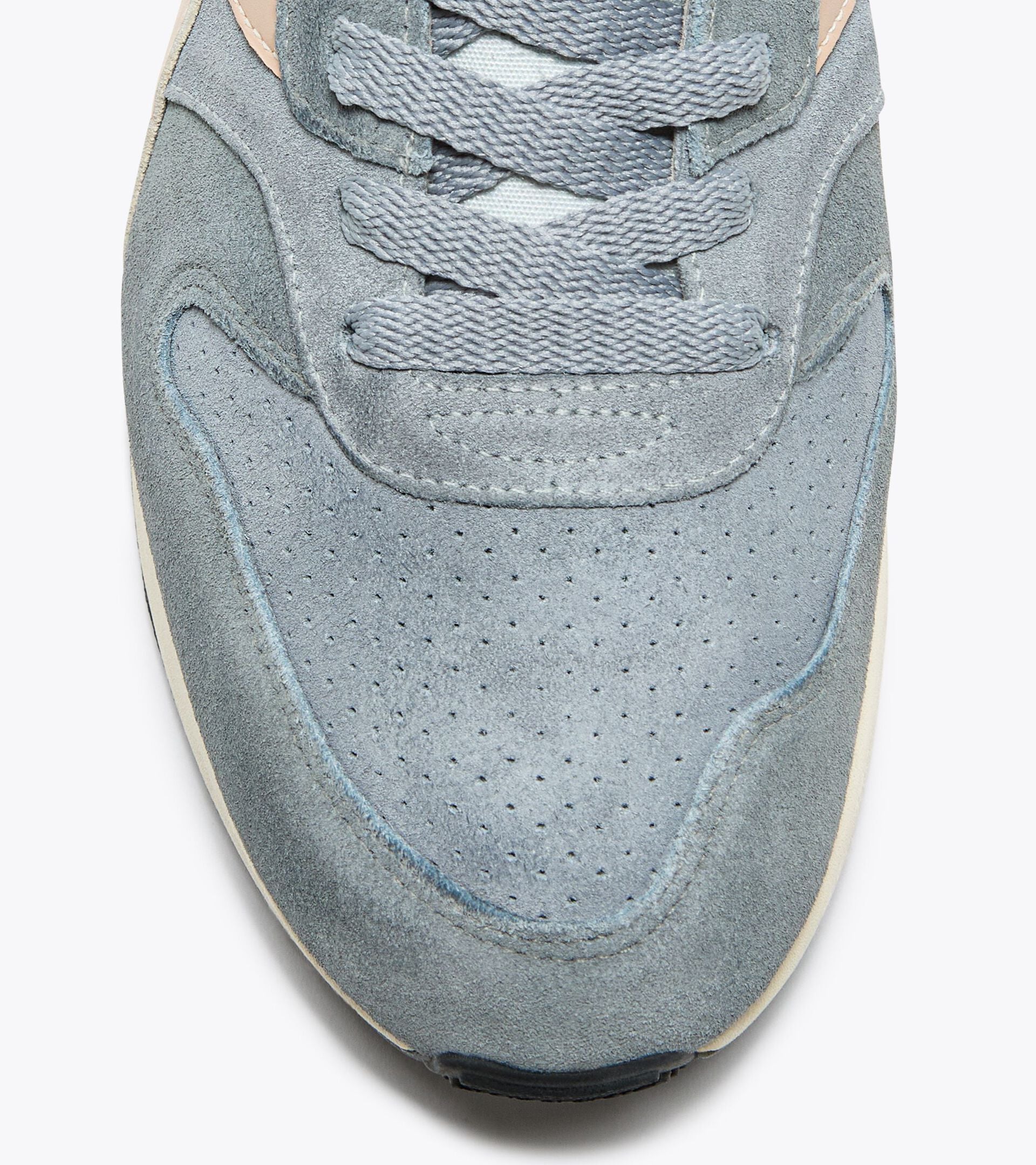 Close-up view of the toe area of an Ace Rivington Diadora Conquest Suede SW sneaker in High Rise color shoe features a light blue suede upper with perforations for breathability and a textured lace-up design. The stitching and material details are visible, highlighting the quality and craftsmanship of the sneaker.