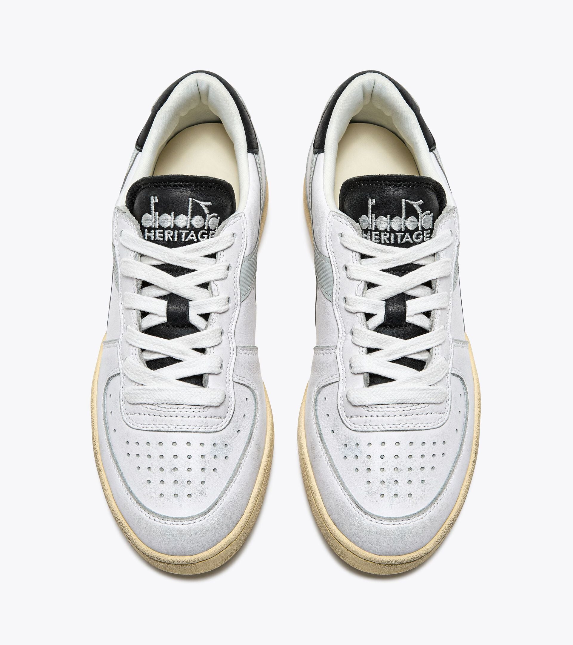 Top view of a pair of Ace Rivington Diadora - Mi Basket Low Used - White/Glacier Gray shoes feature white laces, perforated toe boxes, and black tongue labels with the Diadora Heritage logo.