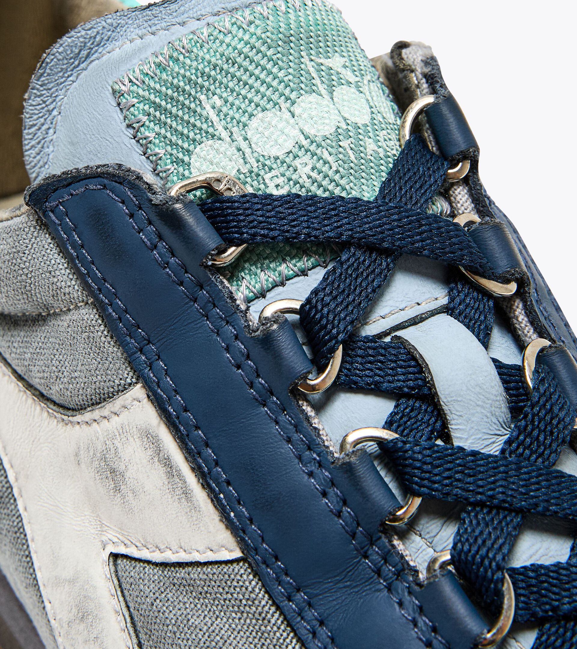 Right-pair upper close-up view of the Ace Rivington Diadora - Equipe Dirty SW EVO - Light Sky Blue highlights the shoe’s detailed craftsmanship, including the blue leather trim, navy blue laces, and the mint green tongue with the Diadora logo. The stitching and metal eyelets are also visible, showcasing the shoe’s quality and design.