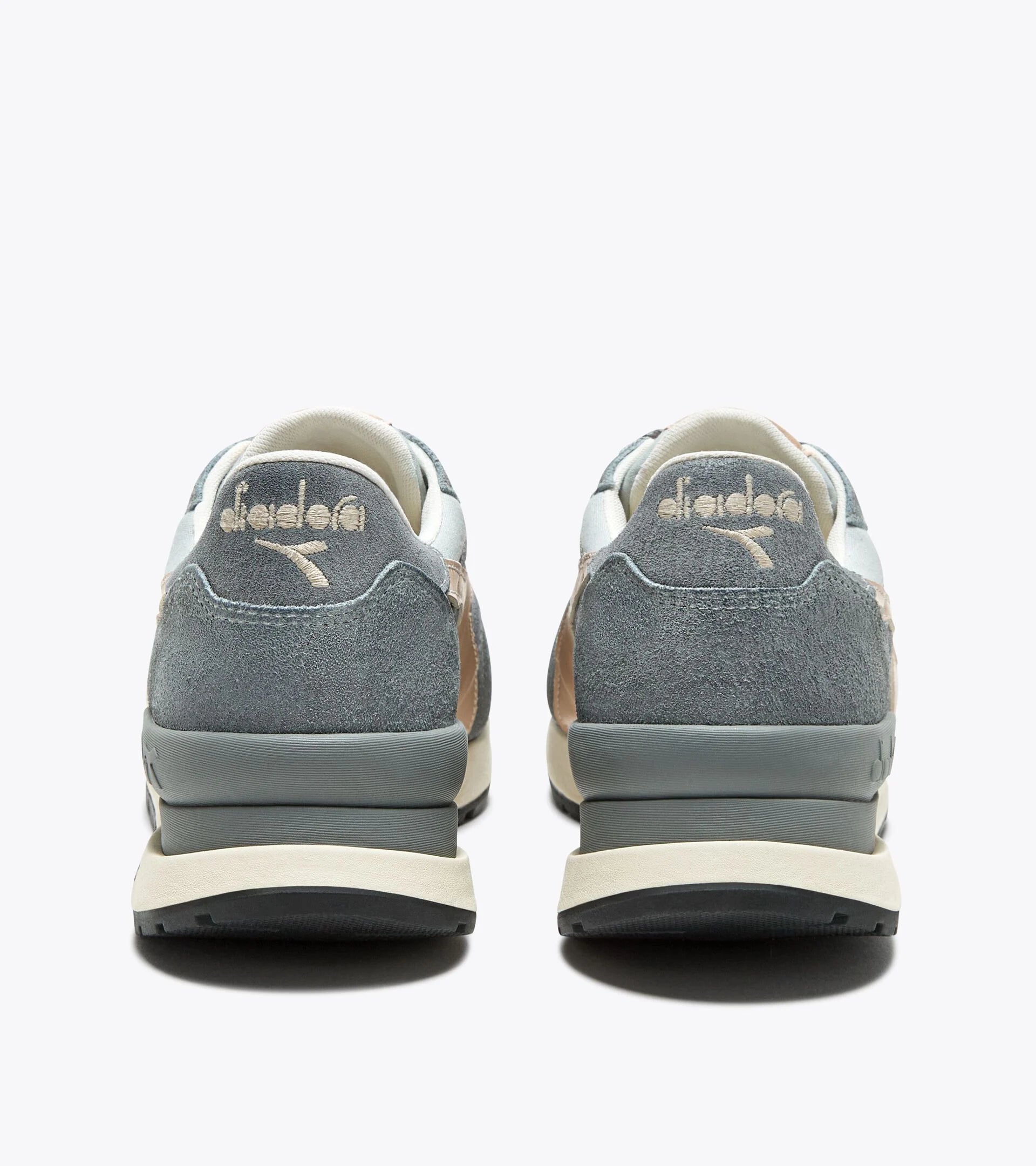 Back view of a pair of Ace Rivington Diadora Conquest Suede SW - High Rise shoes features a combination of grey suede and light blue leather with beige accents. The Diadora logo is prominently displayed on the heel tab of each shoe. The midsole is grey with a beige outsole, providing a stylish and comfortable look.