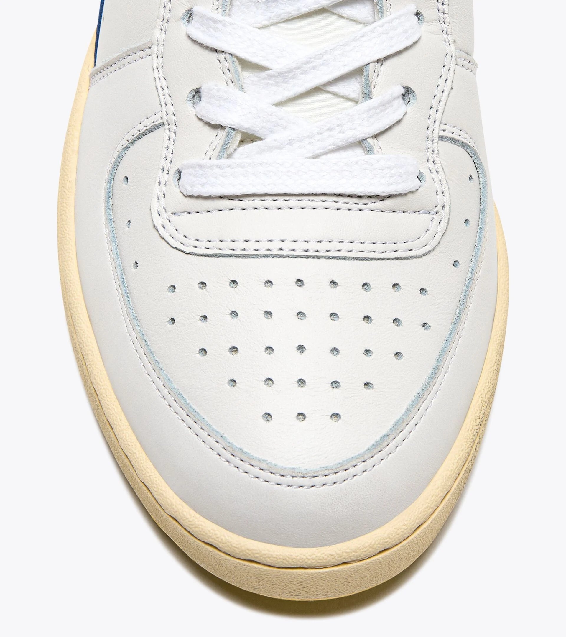 Close-up view of the toe box of an Ace Rivington Diadora Mi Basket Forty Knit Italia - white shoe features white laces, perforations for breathability, and a beige sole. The stitching and craftsmanship are visible, highlighting the quality of the sneaker.