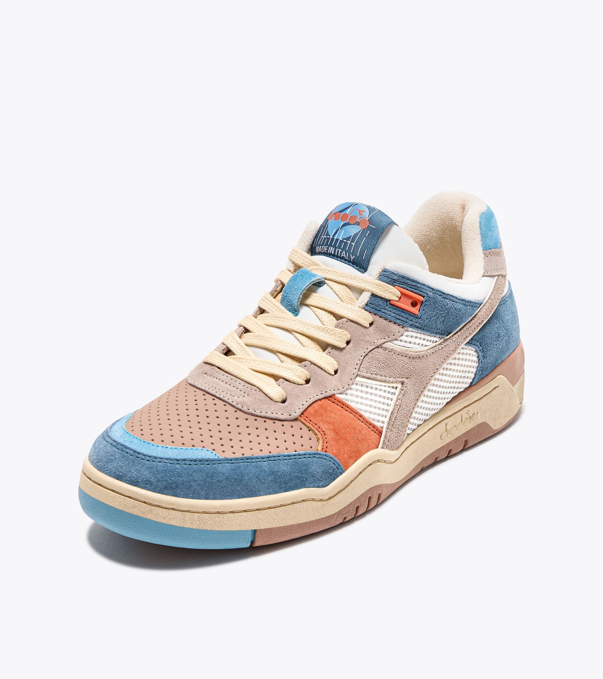 Ace Rivington Diadora B. 560 USED - Tourney Italia sneaker featuring a mix of materials and colors. The shoe has a beige perforated toe box, blue suede overlays, and a combination of beige, orange, and white accents. The midsole is beige with a light blue outsole, and the shoe has beige laces. The tongue displays the Diadora logo and 'Made in Italy' text.