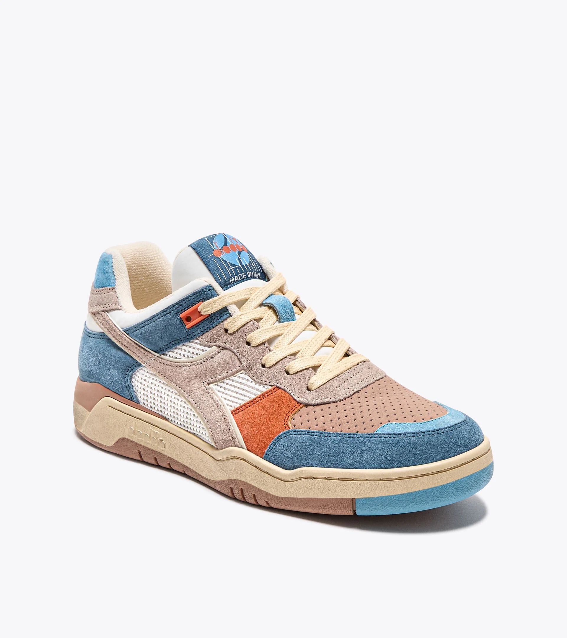 Ace Rivington Diadora B. 560 USED - Tourney Italia sneaker featuring a mix of blue, beige, and orange suede overlays, with a white mesh side panel and beige laces. The shoe has a retro design with a perforated toe box and a blue and orange logo on the tongue.