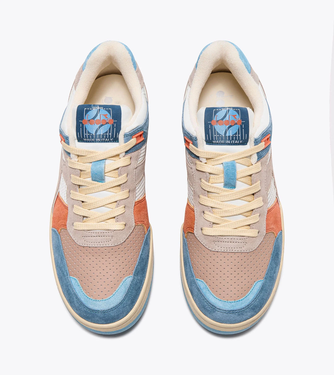 Top view of a pair of Ace Rivington Diadora B. 560 USED - Tourney Italia sneakers featuring a combination of beige, blue, and orange colors with a unique design on the tongue label. The label displays a graphic with the text 'MADE IN ITALY' beneath it.