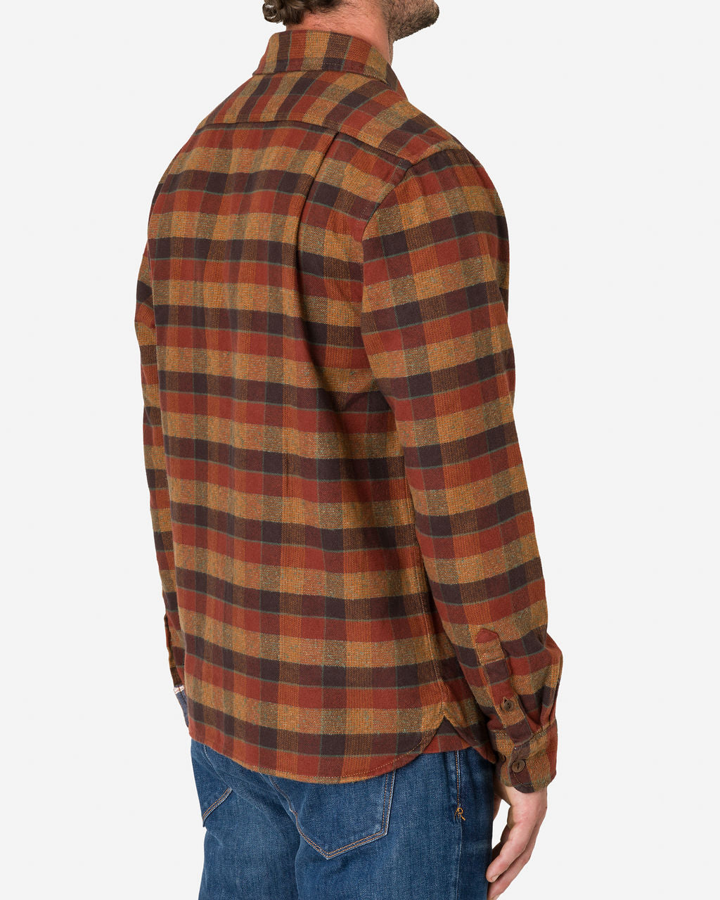 A man is shown from the back, wearing a long-sleeved, button-up flannel utility shirt in a plaid pattern of clay tile colors, featuring shades of brown, red, and yellow paired with blue jeans. The image emphasizes the clothing, showcasing the texture and pattern of the flannel utility shirt by Ace Rivington.