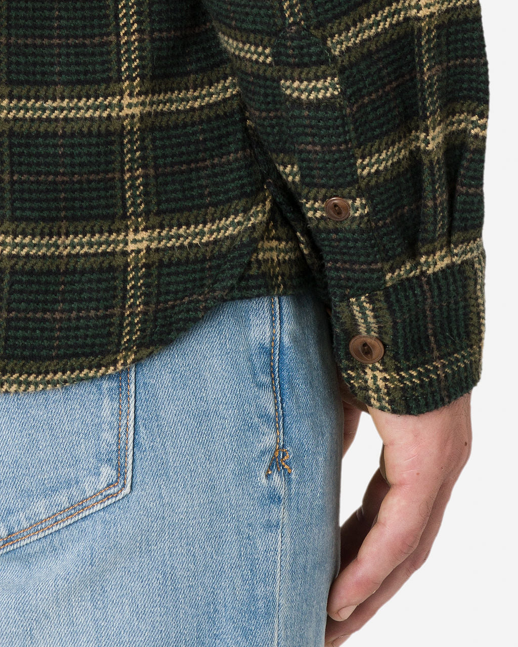 Close-up image of a man wearing a Forest Hound - Flannel Utility Shirt long-sleeve with brown buttons and light blue jeans by Ace Rivington. The person's hand is visible, resting by his side.