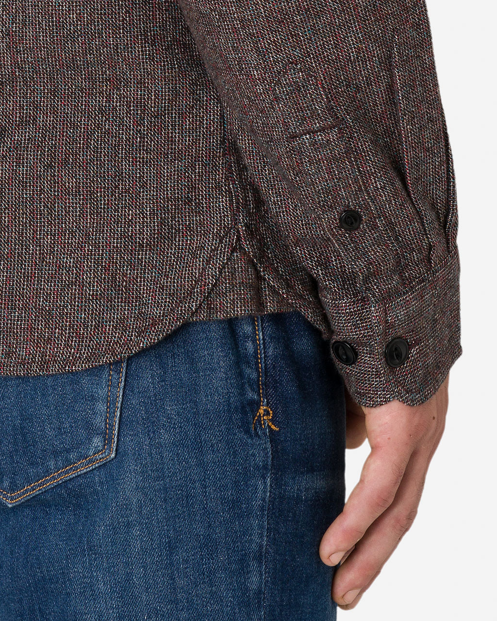 Close-up image of the lower part of a man's waistline and right arm wearing a textured, Ace Rivington iron opal flannel utility shirt long-sleeved with two black buttons on the cuff and blue jeans. The image highlights the details of the clothing, such as the texture and stitching.