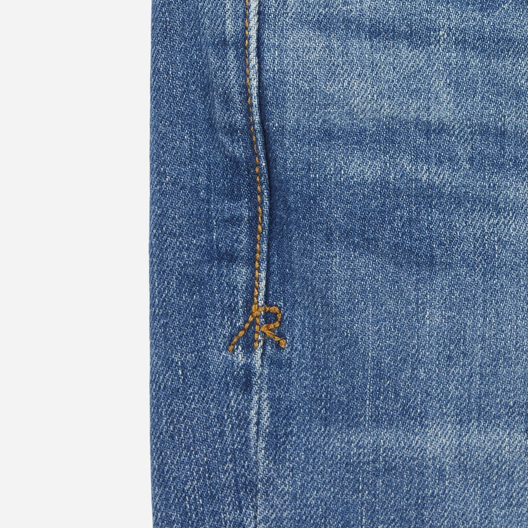 close up of stitching on pair of high quality slim cut men's light blue jeans with slight wear