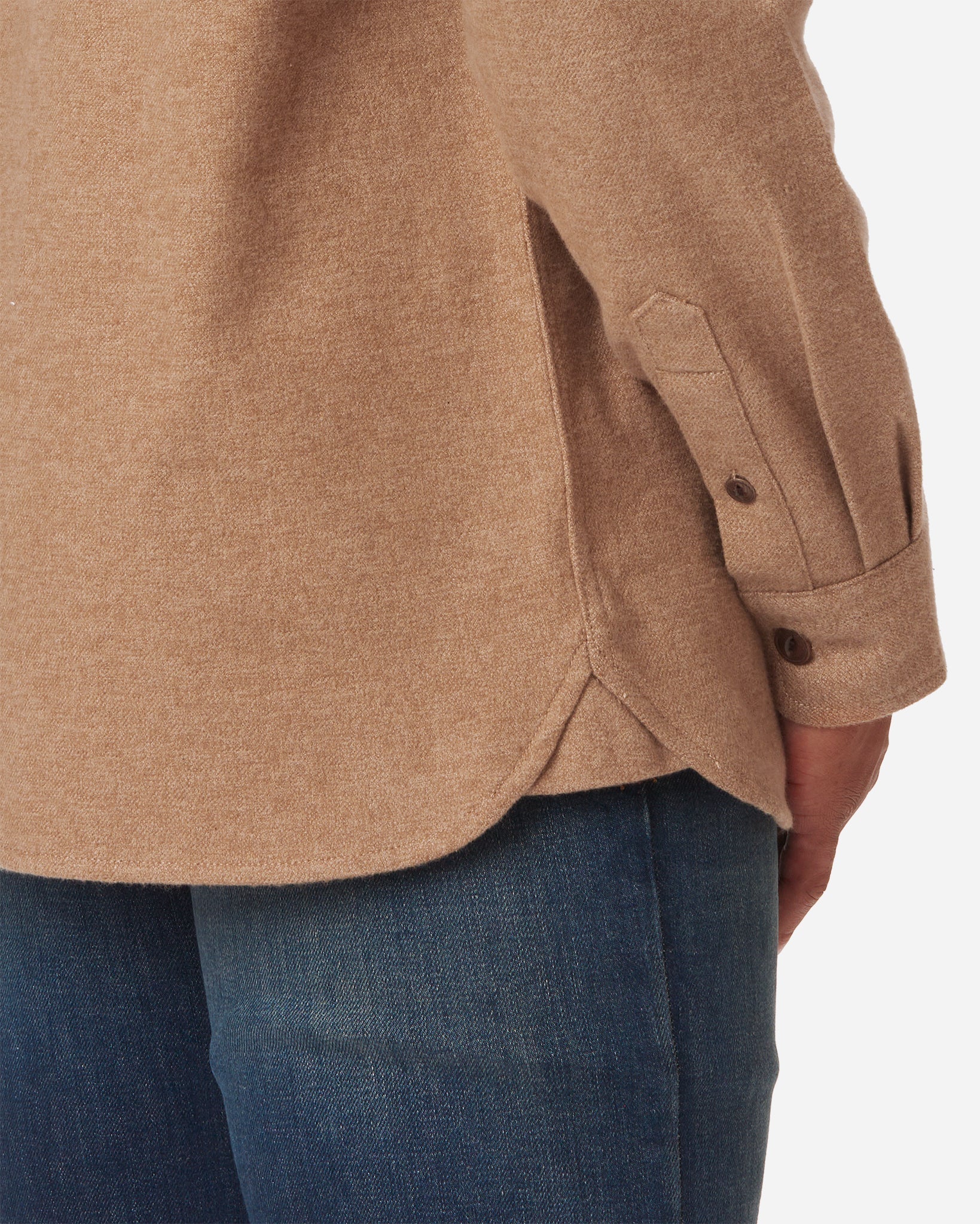 Close-up view of a man's lower back wearing a camel-colored flannel utility H1 shirt paired with blue jeans by Ace Rivington, featuring a curved hem and side slit, with buttoned cuffs on the sleeves.