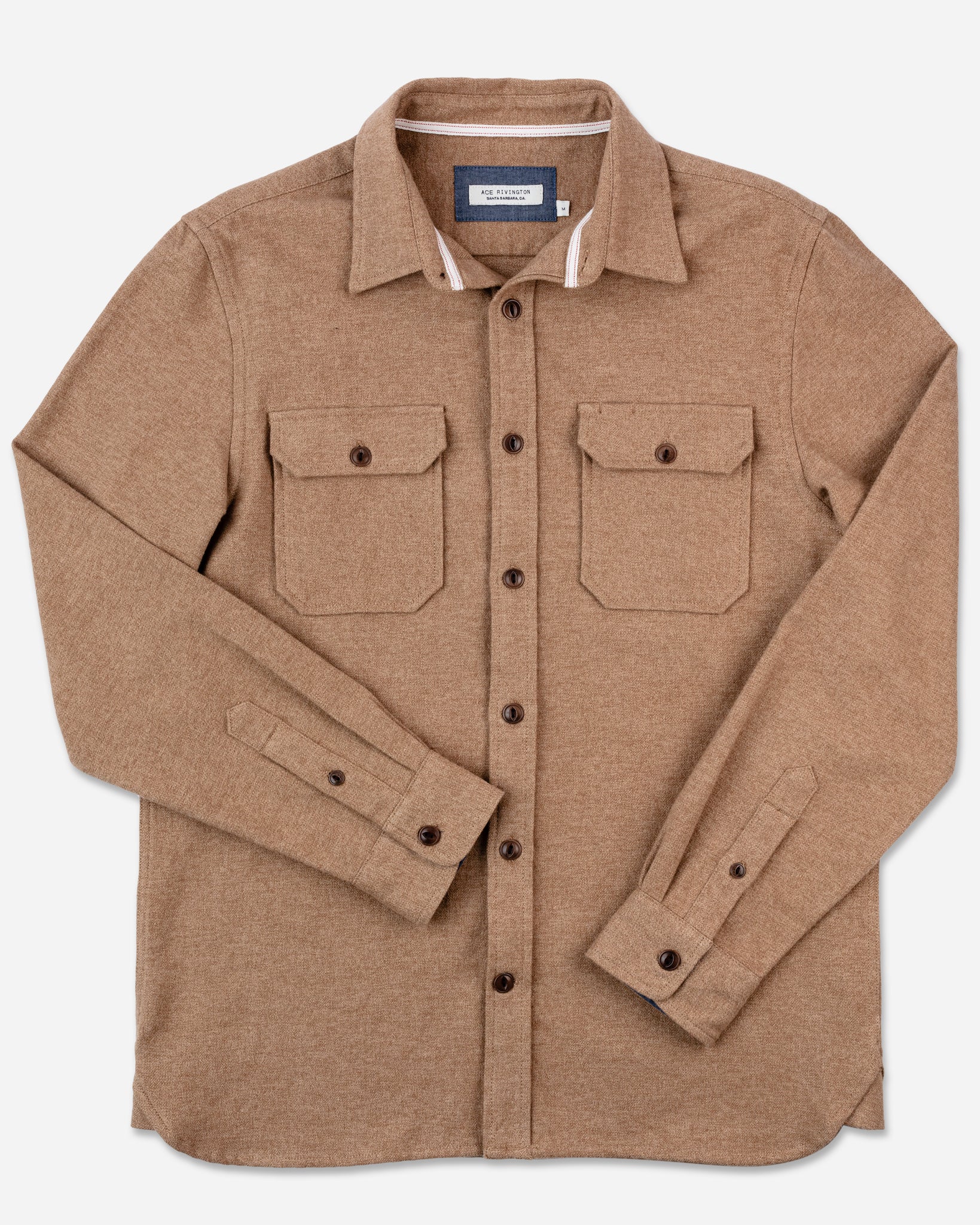 A camel-colored flannel utility shirt by Ace Rivington features long sleeves and a button-up design, complete with two chest patch flap pockets. Made from 100% cotton, this heavy brushed flannel fabric offers an exceptionally soft feel. The shirt includes a classic collar and Corozo cat-eye buttons. It is displayed flat against a plain white background to highlight its design and details.