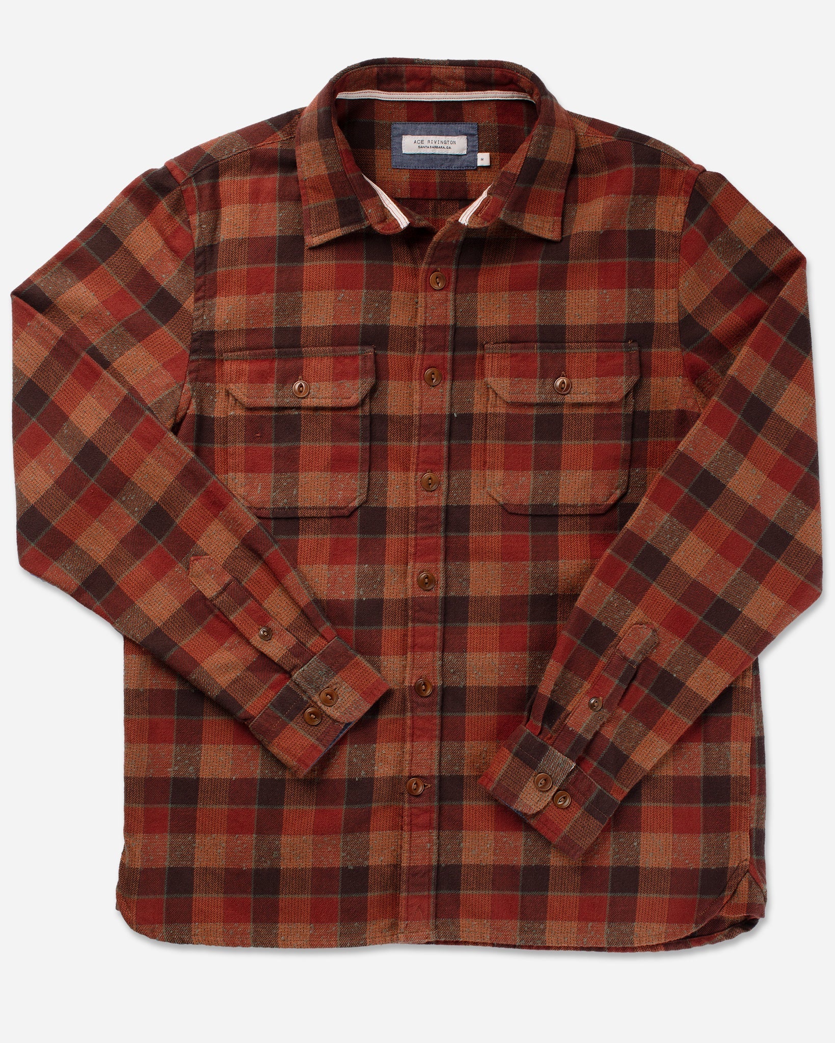 Ace Rivington's flannel utility long-sleeve shirt comes in a clay tile color and features a plaid pattern in shades of red, brown, and orange. It includes two chest flap pockets with button closures and buttoned cuffs. Made of 100% heavy brushed cotton flannel, the shirt offers a super soft feel and has been heavily pre-washed to minimize shrinkage. Additional details include Corozo cat-eye buttons and chambray trim. The design is showcased by laying the shirt flat on a plain white background.