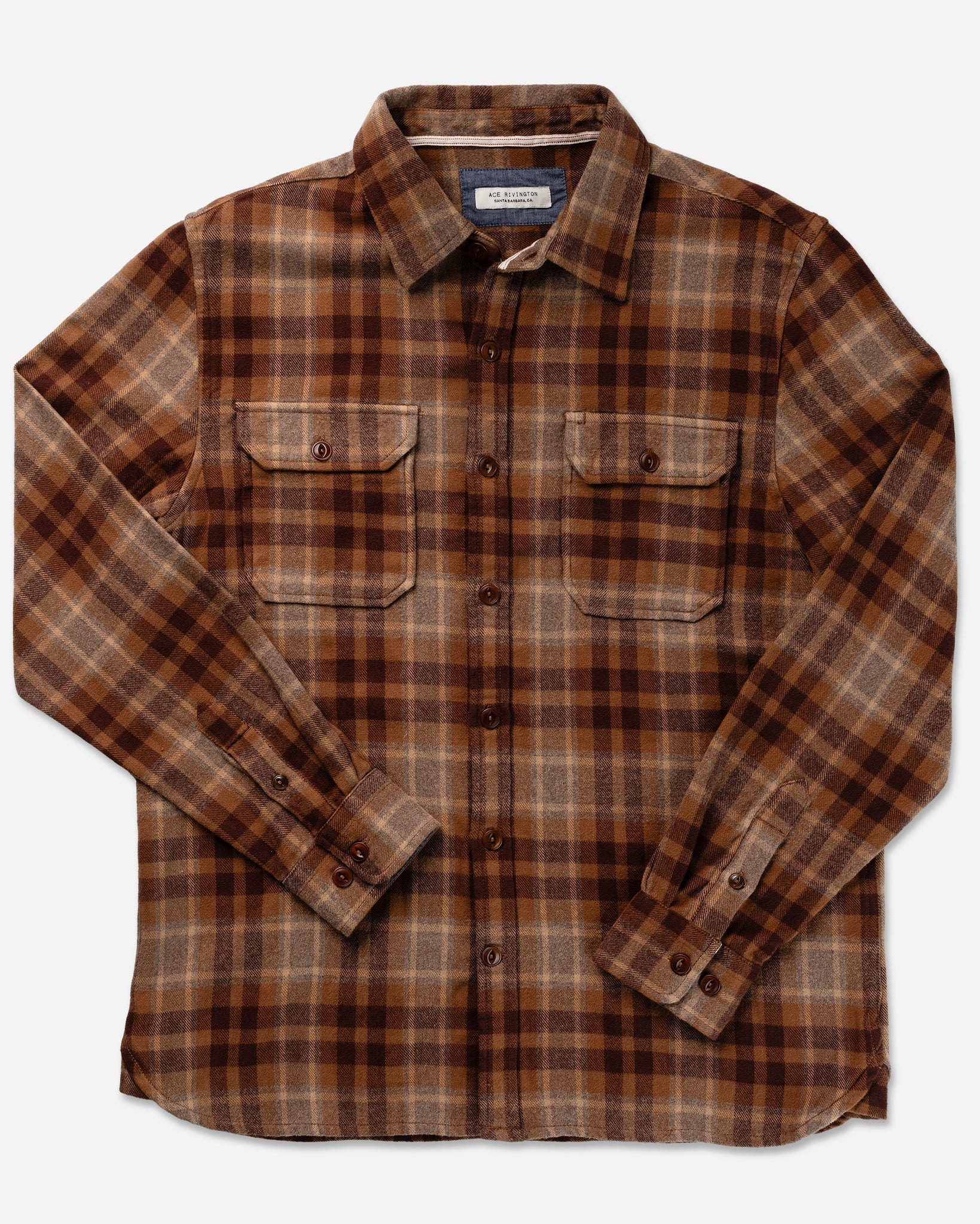 Ace Rivington Desert Bark Flannel Utility Shirt features long sleeves, a button-up front, and two chest flap pockets with buttoned flaps. Made from 100% cotton heavy brushed flannel, it offers a soft feel and has been pre-washed to prevent shrinkage. Accented with Corozo cat-eye buttons and chambray trim, it's perfect for cooler weather. The shirt is shown flat against a plain white background.