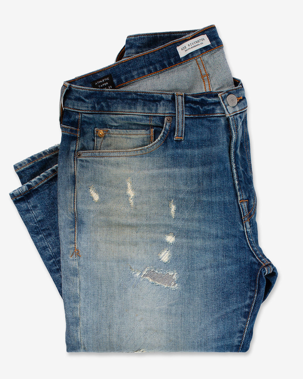 A pair of folded Athletic Taper Denim Jeans - Houston with a distressed and faded design, featuring visible wear and tear marks on the front.