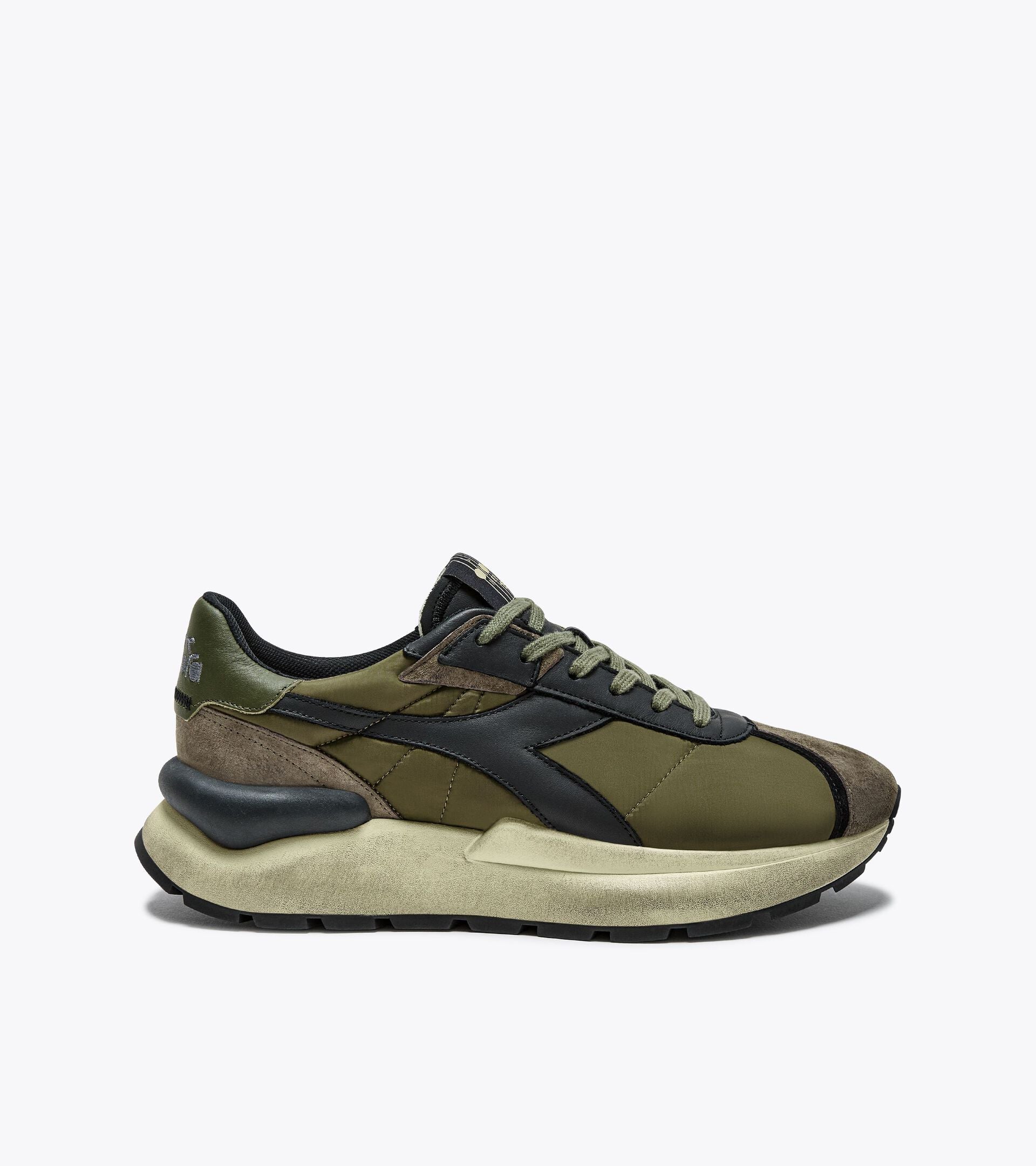 Right-pair side view of the Ace Rivington Diadora - Mercury Elite - Beech Green, featuring a retro-inspired design with a textile and leather upper, waxed cotton laces, and an oversized stabilizer for a modern touch. The olive green and brown colorway reflects 1970s athletic shoe aesthetics.