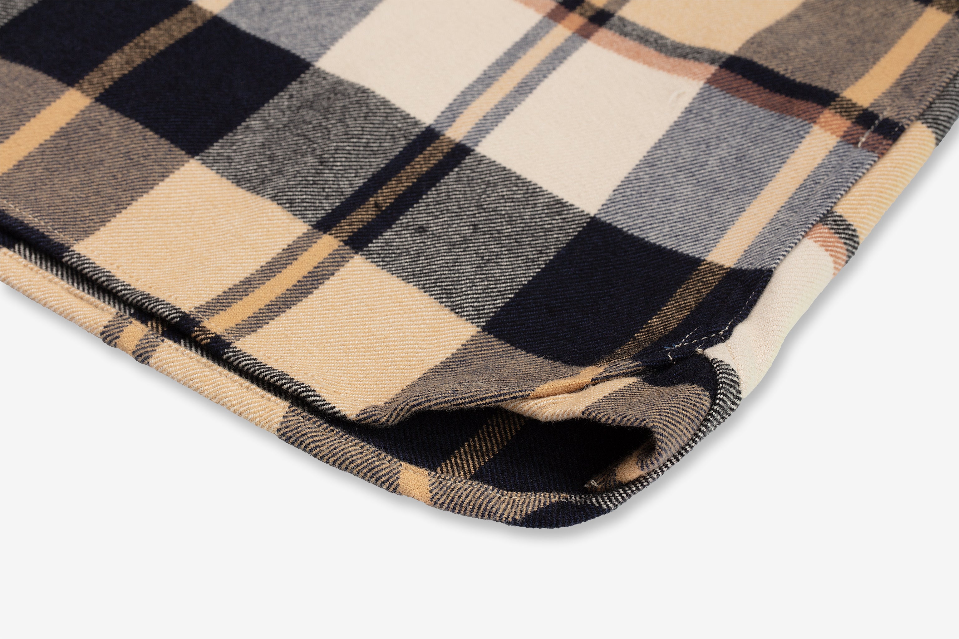 Close-up of the folded fabric of Ace Rivington Midnight Dune - Flannel Utility Shirt with a beige, black, gray, and yellow checkered pattern. The fabric has a neat hem, highlighting its quality and detailed craftsmanship. The checkered design showcases the intricate weaving of the colors, providing a visually appealing texture.