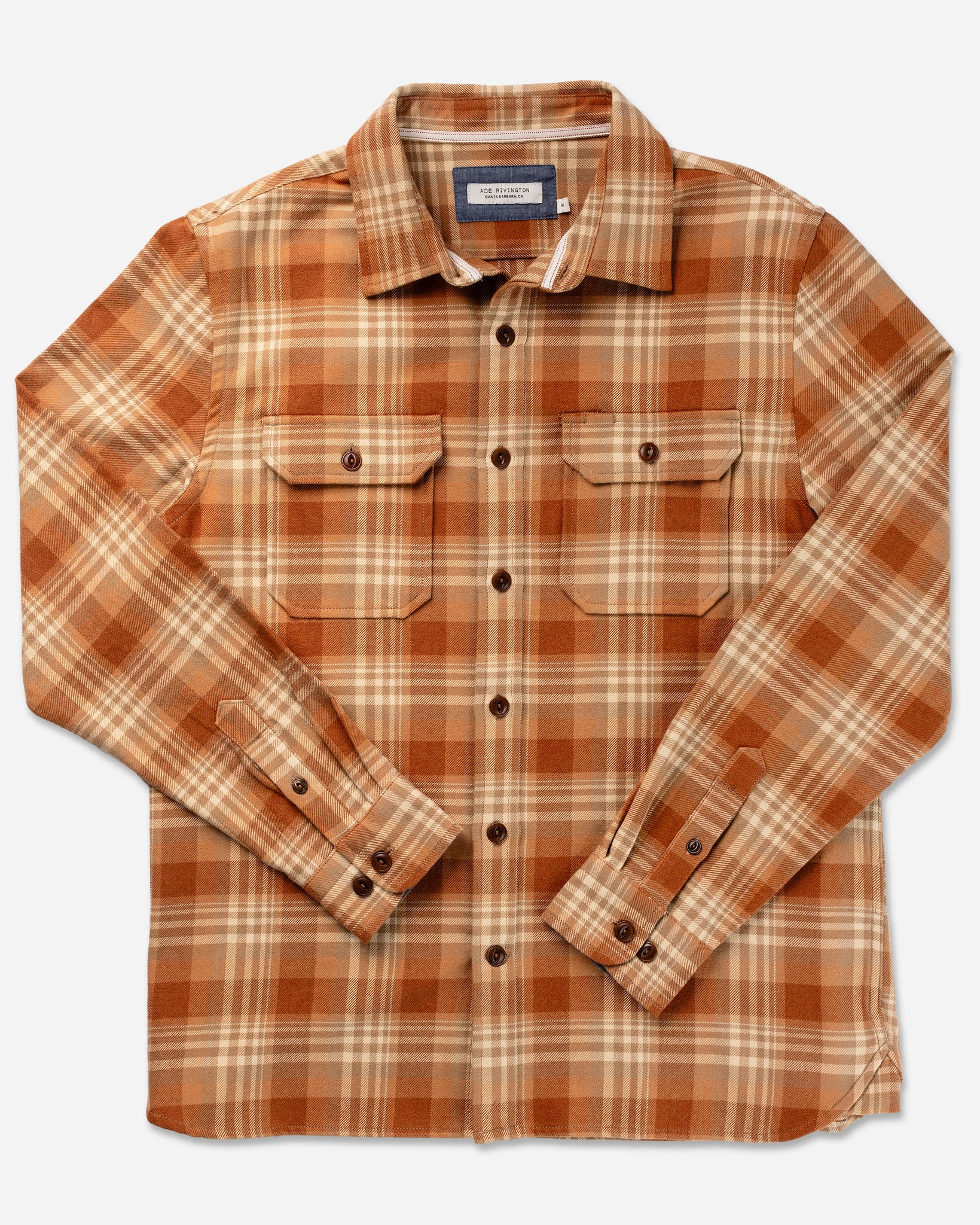 Ace Rivington long-sleeve, button-up flannel utility shirt—sand storm color with a plaid pattern in shades of brown, orange, and beige. It features two chest pockets with buttoned flaps, a collar, and buttoned cuffs. Made from 100% cotton heavy brushed flannel, it offers a super soft hand feel and has been heavily pre-washed to eliminate shrinkage. The shirt is ideal for casual or outdoor wear, providing warmth and comfort.