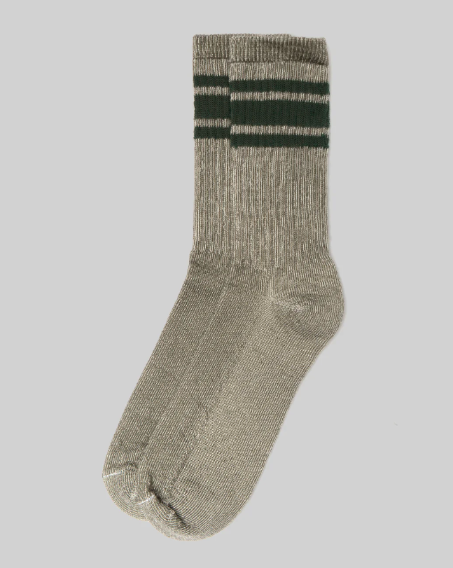 A pair of light gray American Trench Merino Activity Socks features three dark green horizontal stripes near the top and a ribbed texture. The socks are displayed against a plain white background.