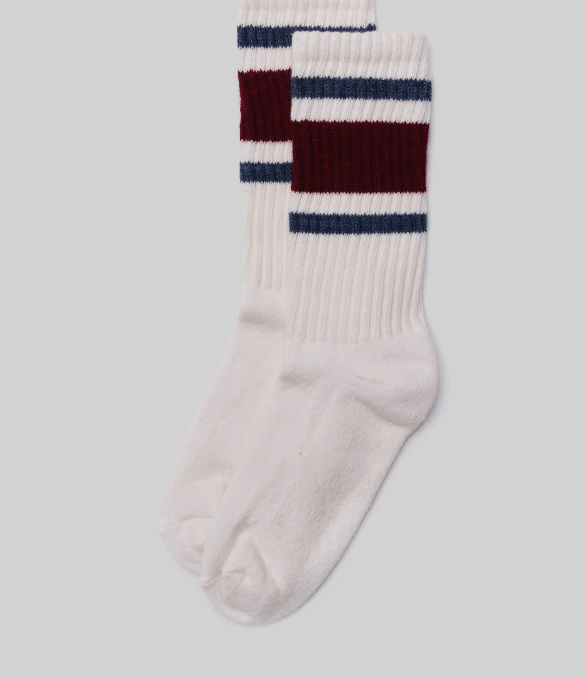 A pair of Ace Rivington American Trench Retro Stripe white socks with a ribbed upper section featuring retro stripes in maroon and dark blue. The design is reminiscent of vintage athletic socks, adding a nostalgic and stylish touch.