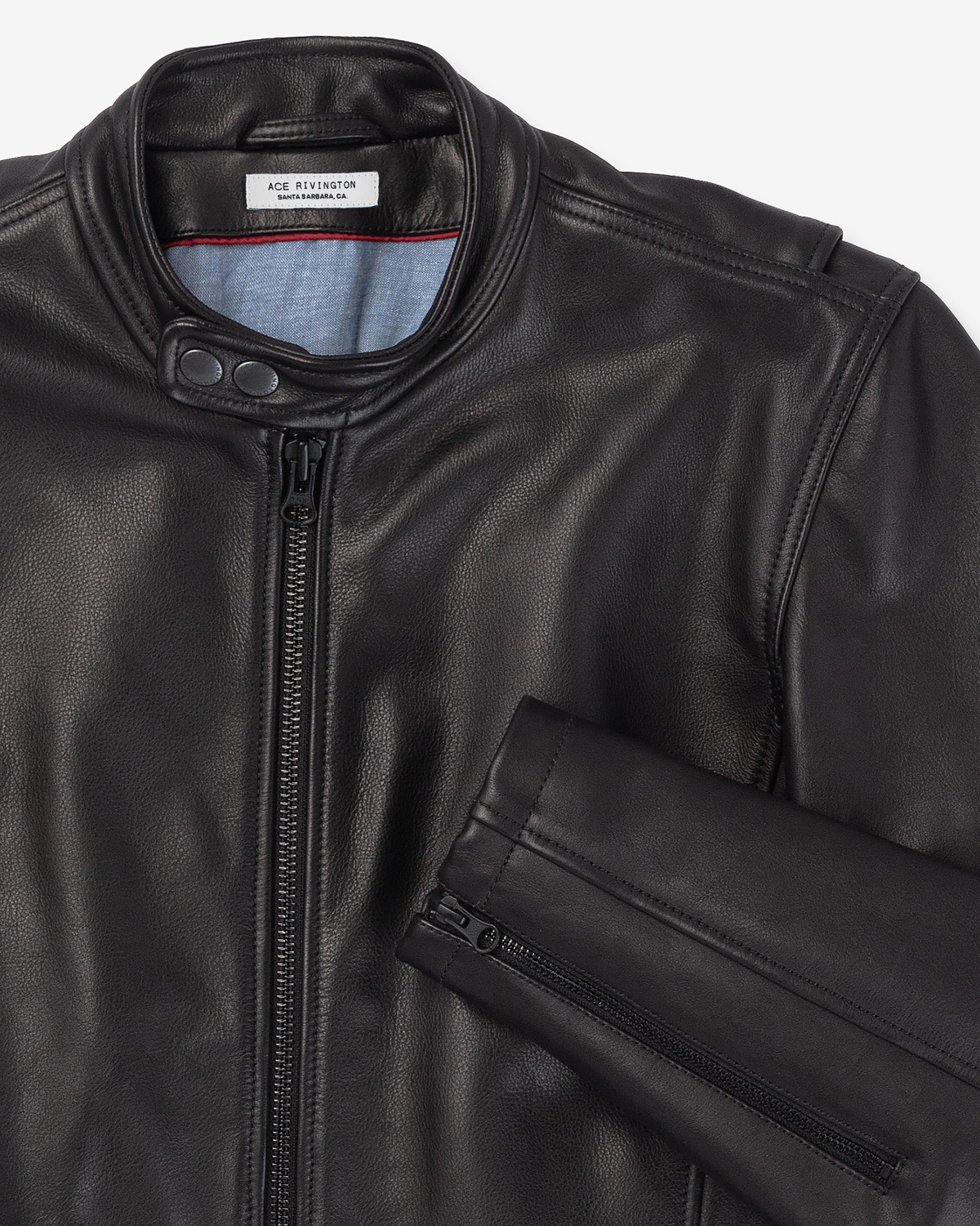 A close-up view of Cowhide Vintage Black color - Cafe Racer Jacket with a front zipper and a snap-button collar. The jacket has a visible label inside the collar that reads 'ACE RIVINGTON'. The sleeve is partially visible, showing a zipper detail on the cuff.