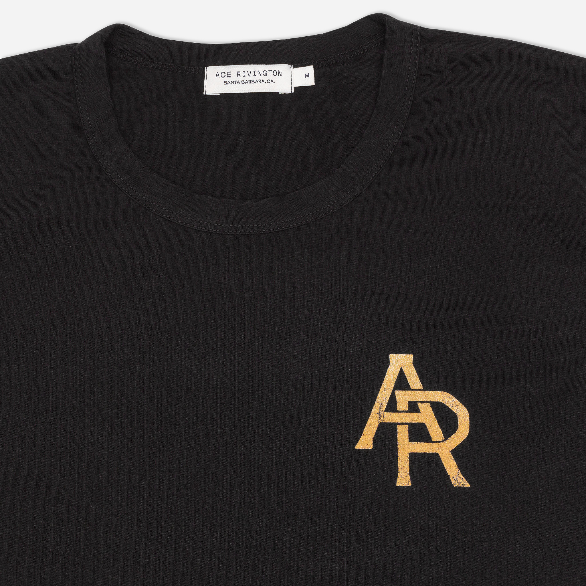 Black Supima Tee Crewneck short sleeves Vintage Flyer t-shirt features a small, gold-colored 'AR' logo on the left chest. The label inside the collar reads 'ACE RIVINGTON SANTA BARBARA, CA' and indicates the size as 'M'.