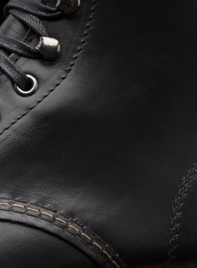 Close-up view of a black leather Ace Rivington Wolverine - 1000 Mile - Plain Toe Original Boot focuses on the detailed stitching and metal eyelets for the laces, showcasing the craftsmanship and quality of the leather material.