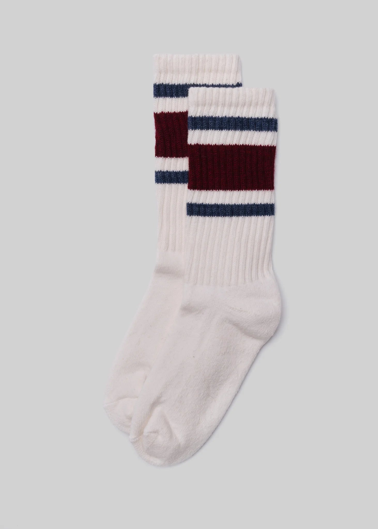 A pair of Ace Rivington American Trench Retro Stripe white socks with a ribbed upper section featuring retro stripes in dark red and blue. The design is reminiscent of vintage athletic socks, adding a nostalgic and stylish touch.