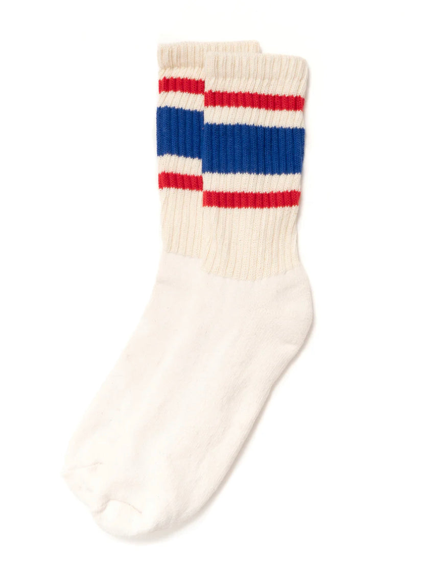 A pair of Ace Rivington American Trench Retro Stripe white socks with a ribbed upper section featuring retro stripes in red, white, and blue. The design is reminiscent of vintage athletic socks, adding a nostalgic and stylish touch.