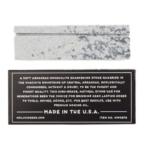 Ace Rivington Mollyjogger - Ironquill Hook and Knife Sharpening Stone shows a rectangular sharpening stone with a speckled gray and white pattern. Below the stone is a black label with white text describing the product information including: 'A soft Arkansas novaculite sharpening stone quarried in the Ouachita Mountains of Central Arkansas, high-grade, natural stone, for best results use with premium honing oil, Made in the U.S.A.'